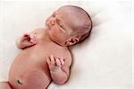 Cute one week old baby boy asleep on bed