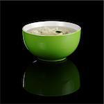 Chinese noodle soup in a green bowl photographed on black with a reflection