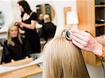 Hairdresser in action with blond customer close up