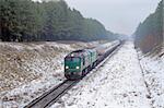 Freight diesel train passing the snowy forest