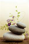 pebbles pyramid on a rock with floral design at the background - beige background