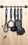 Set of black modern kitchen utensil hanging on wooden background