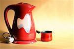Modern red electric kettle and coffeepot standing on nice yellow background