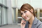 Attractive business woman using cellphone, half length closeup portrait in outside of modern buildings.