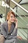 Young business manager woman holding cellphone and sitting, half length closeup portrait outside of modern buildings.