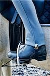 Woman's leg with blue jodhpurs and black riding boots with foot in stirrup