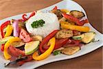 Ratatouille of zucchini, eggplant, tomato, bell pepper and onion with cooked rice and parsley on top (Selective Focus, Focus on the front of the rice, the parsley on top and the vegetable around)