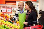 Shop assistant holding apple with customer in the supermarket