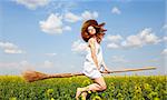 Redhead enchantress flying over spring rapeseed field on broom.