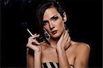 Elegant brunette woman smoking a cigarette on black background