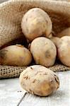 Bag of organic potatoes on a wooden background