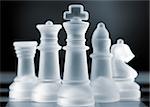 glass chess pieces is standing on board in dark
