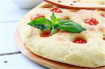 Italian Focaccia bread with tomatoes and basil on a cutting board