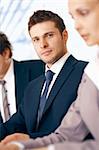 Young confident businessman sitting on the meeting at the office with colleagues.