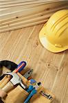 Construction background. Yellow helmet and tool belt on wooden floor.