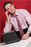 Smart businessman talking over the cellphone with laptop on the table