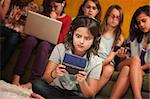 Wide-eyed little girl with headphones and game console with friends