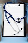 Note pad and stethoscope on a blue and dark background