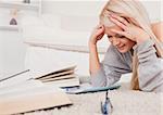 Attractive blond woman lying on a carpet being angry with her computer in the living room