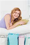 Smiling woman lying on the couch with her shopping bags in the living-room