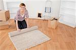 Attractive woman rolling up a carpet to prepare to move house