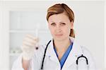 Blond-haired scientist looking at the camera while holding a red test tube in a lab