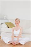 Young smiling woman doing relaxation exercises while sitting on the floor in the living room