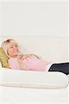 Good looking blonde female posing while lying on a sofa in the living room
