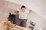 Top view of a happy handsome man with carpentry tools around