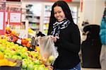 Portrait of a happy young woman buying apple in the supermarket