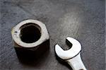 Nut and spanner on metal workbench background