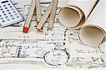 the blueprint of a house with two paper rolls, a calculator and a rule