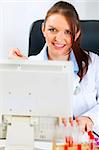 Smiling medical doctor woman sitting at office table and working on computer