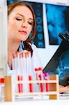 Pensive medical doctor woman sitting at office table and looking patients roentgen