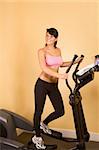 Young woman in sporty outfit sweaty while working out on elliptical machine