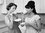 Two retro-styled women drinking coffee in kitchen