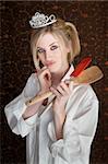 Beautiful Caucasian woman with hand on chin holding spatulas