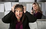 Frustrated female office worker in a cubicle pulls her hair