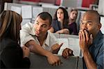 Embarrassed man with hand over mouth standing with coworkers