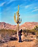 Young Navajo woman honoring life in the desert in front of a saguaro cactus