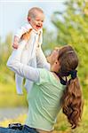 Happy young mother playing with laughing baby girl in park