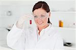 Cute red-haired scientist looking at a test tube in a lab