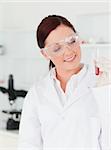 Pretty red-haired scientist looking at a test tube in a lab