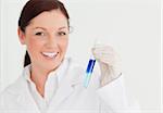 Smiling scientist looking at the camera while holding a  test tube in a lab