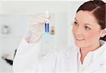 Smiling red-haired scientist looking at a test tube in a lab
