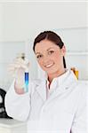 Good looking red-haired scientist looking at the camera while holding a test tube in a lab