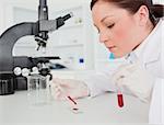 Cute red-haired female scientist doing an experiment in a lab