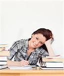 Attractive joyful red-haired girl studying for an examination at her desk