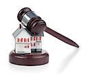 Closeup of a toy house model and a brown gavel against a white background