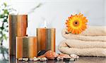 Lighted candles with an orange gerbera on towels and sea shells